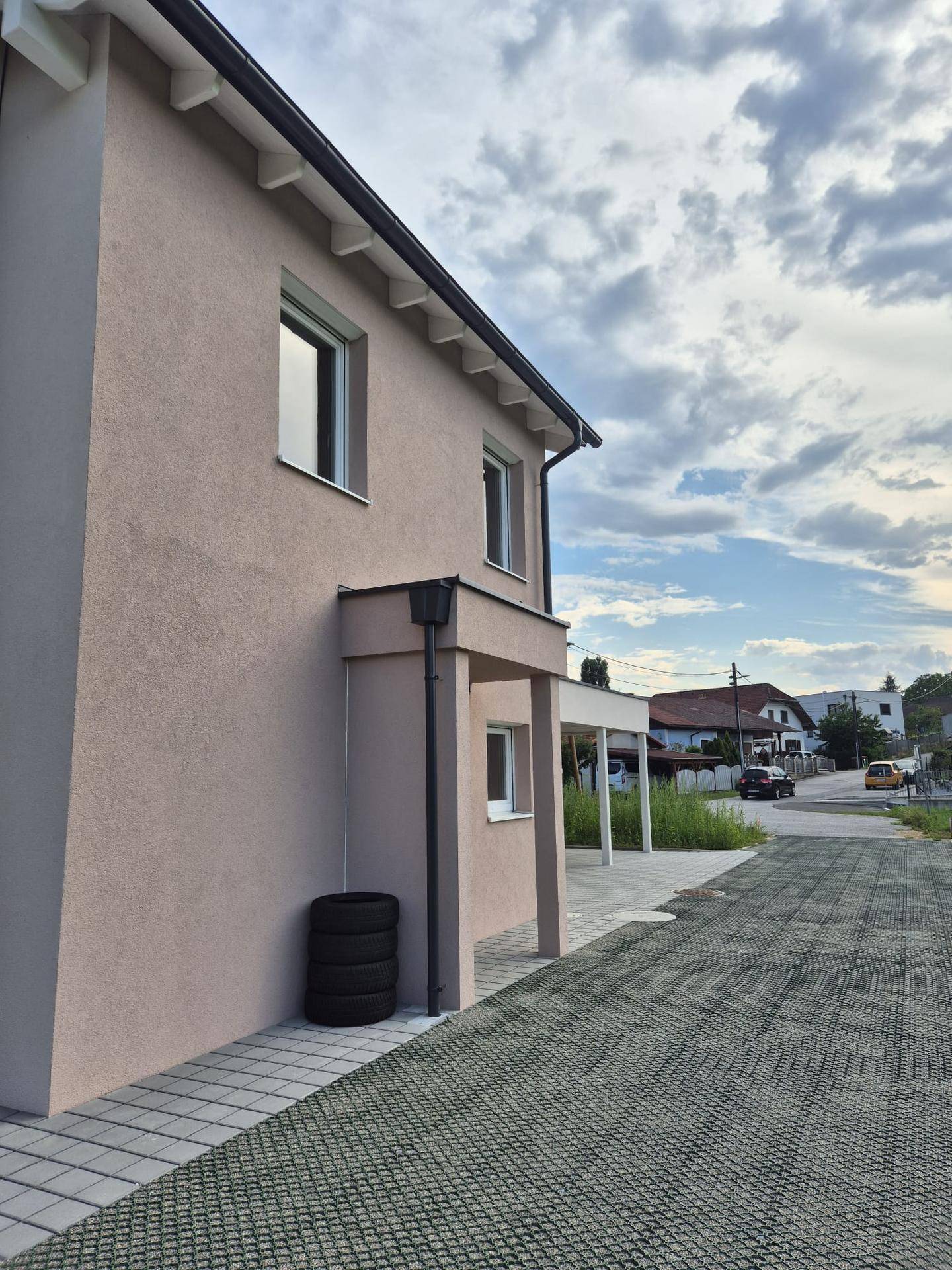 Seitenfassade des Neubaus mit Eingangsbereich und Blick auf die angrenzende Straße.