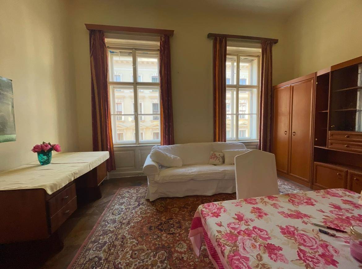 Helles Wohnzimmer mit klassischem Teppich, weißem Sofa und Blick auf die umliegenden Gebäude.