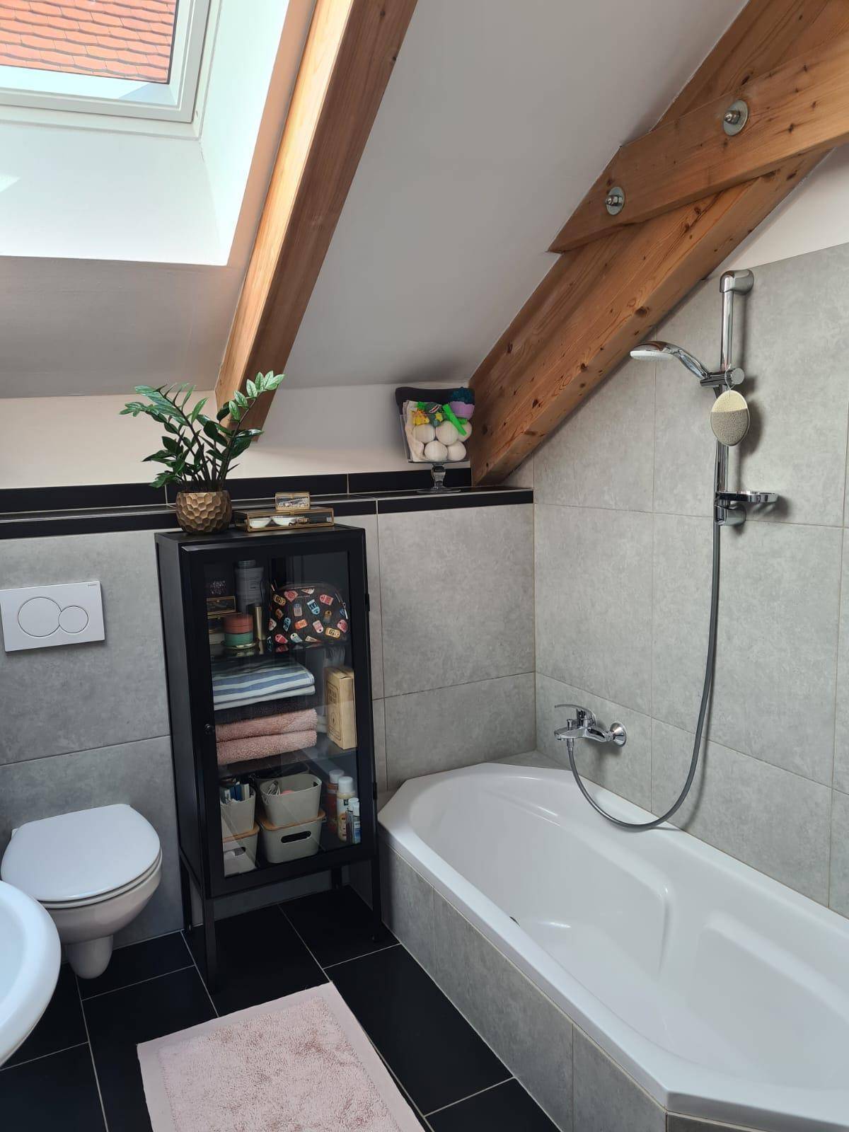Helles Badezimmer im Dachgeschoss mit Badewanne, Dusche, Toilette und praktischem Stauraum.
