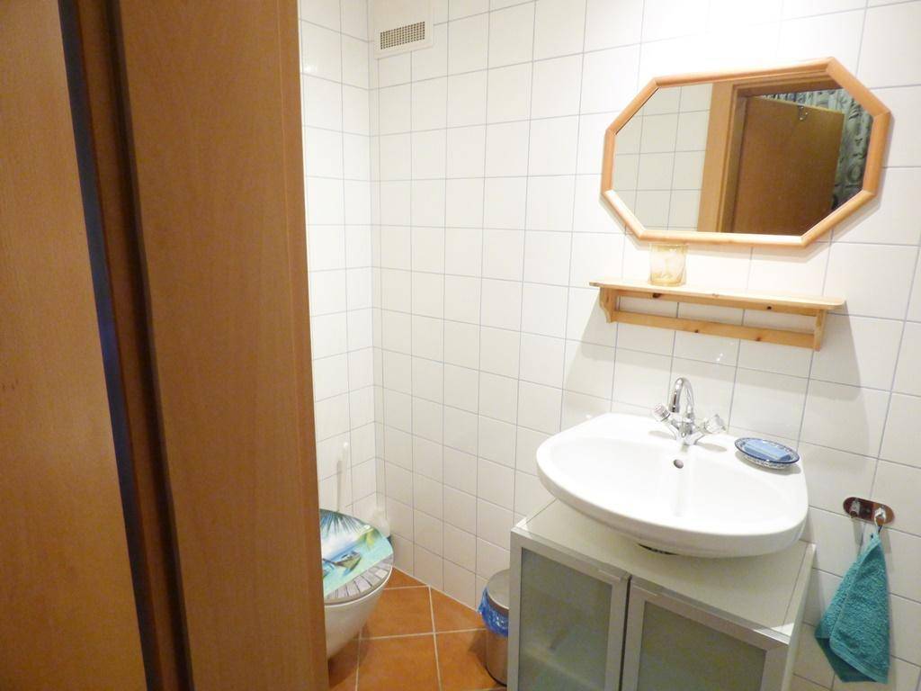 Kleines WC mit Waschbecken, Spiegel und weißen Fliesen.