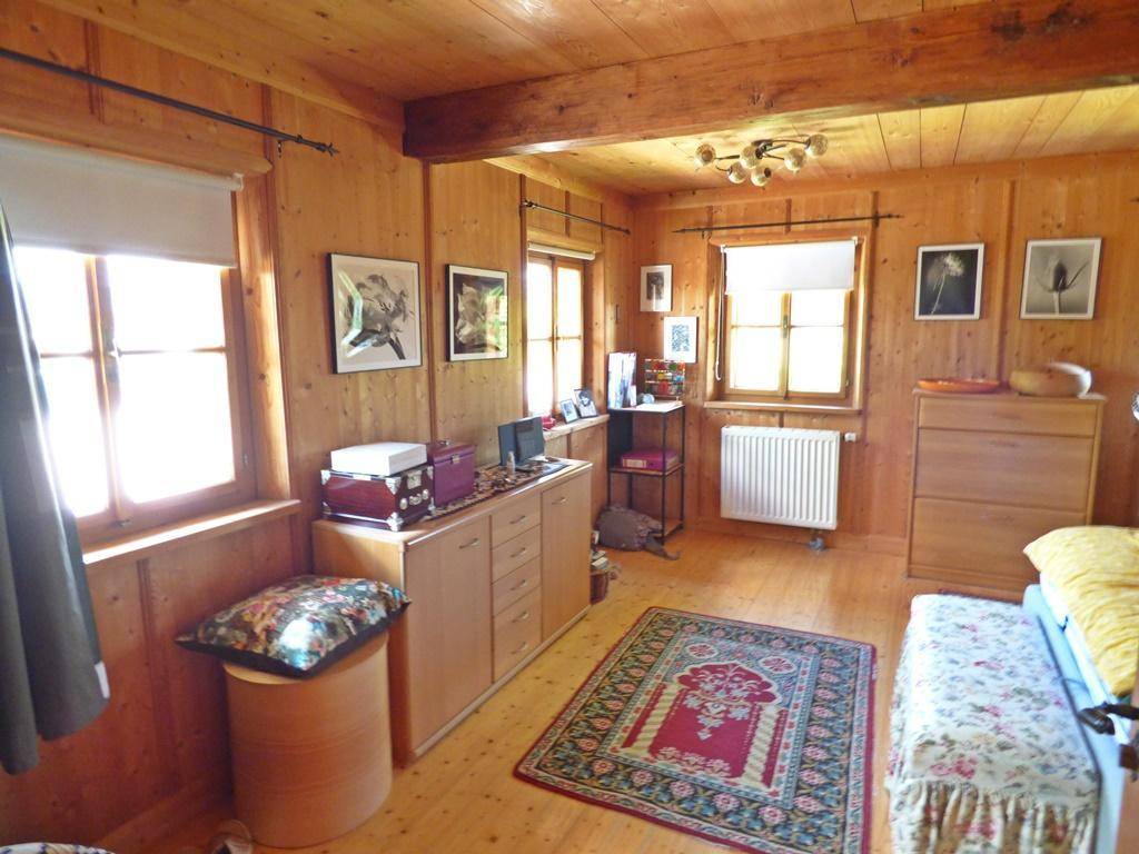 Schlafzimmer mit Holzwänden, Holzboden und traditionellem Teppich.