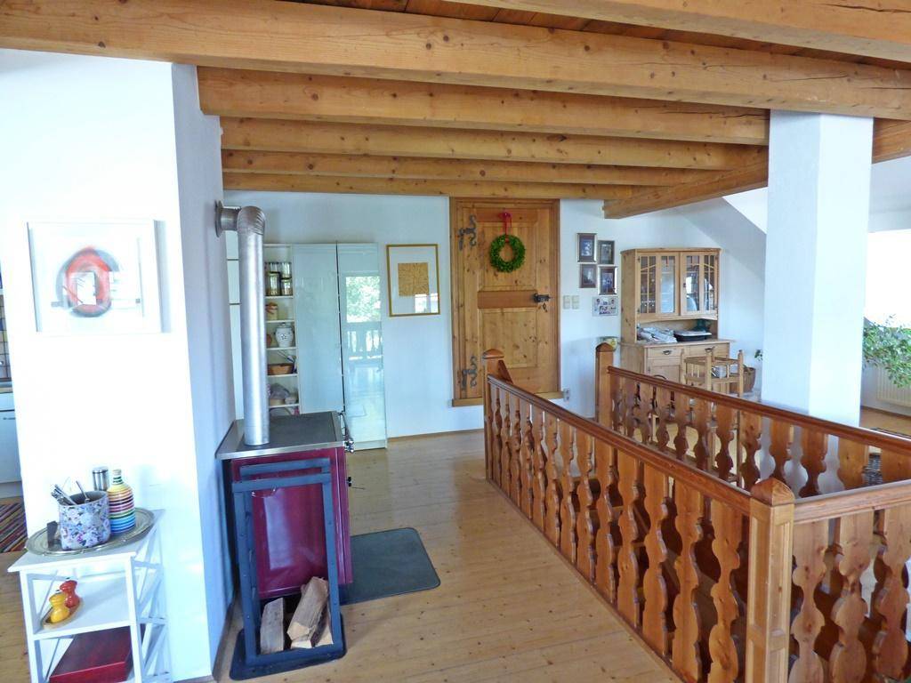 Heller Flur mit Kaminofen, Holzbalken und Zugang zu weiteren Räumen.