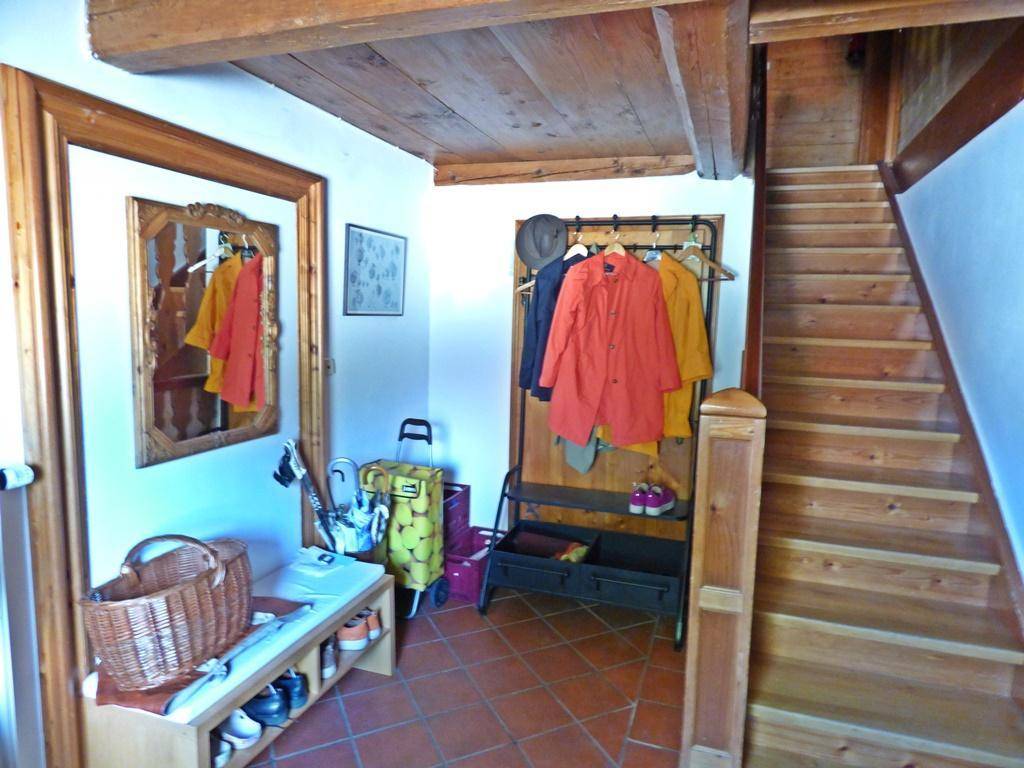 Eingangsbereich mit Garderobe, Holztreppe und Terrakottafliesen.