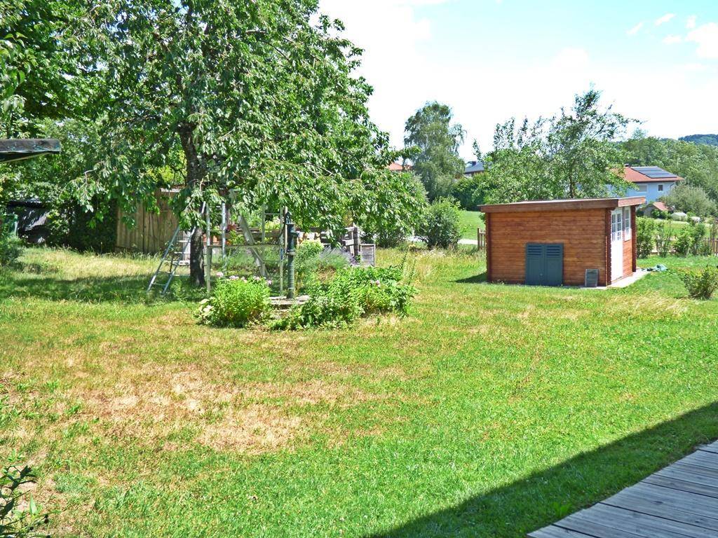 Großer Garten mit Rasenfläche, Bäumen und einem Gartenhaus.