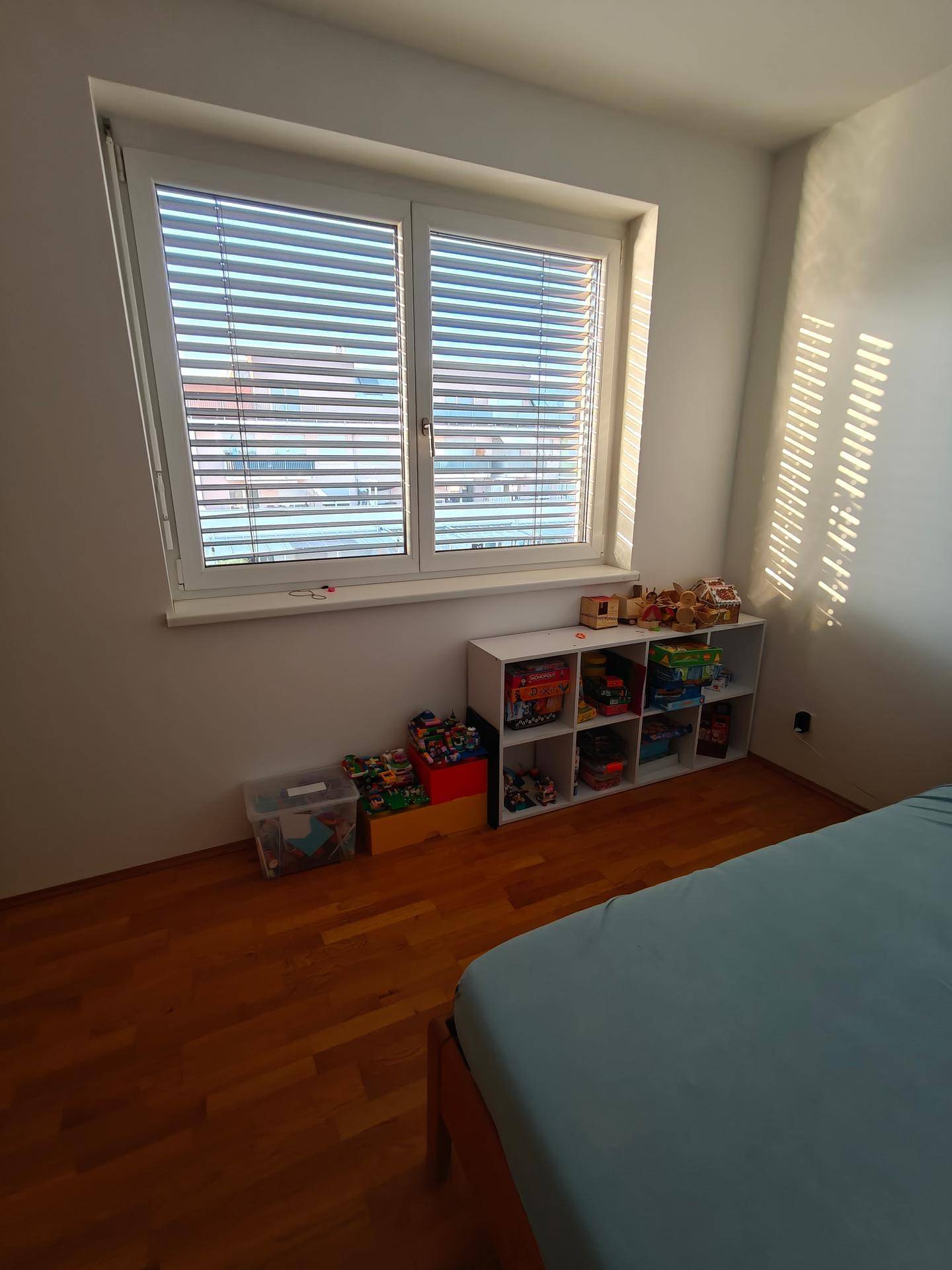 Großes Fenster im Schlafzimmer mit Jalousien, das viel natürliches Licht hereinlässt.