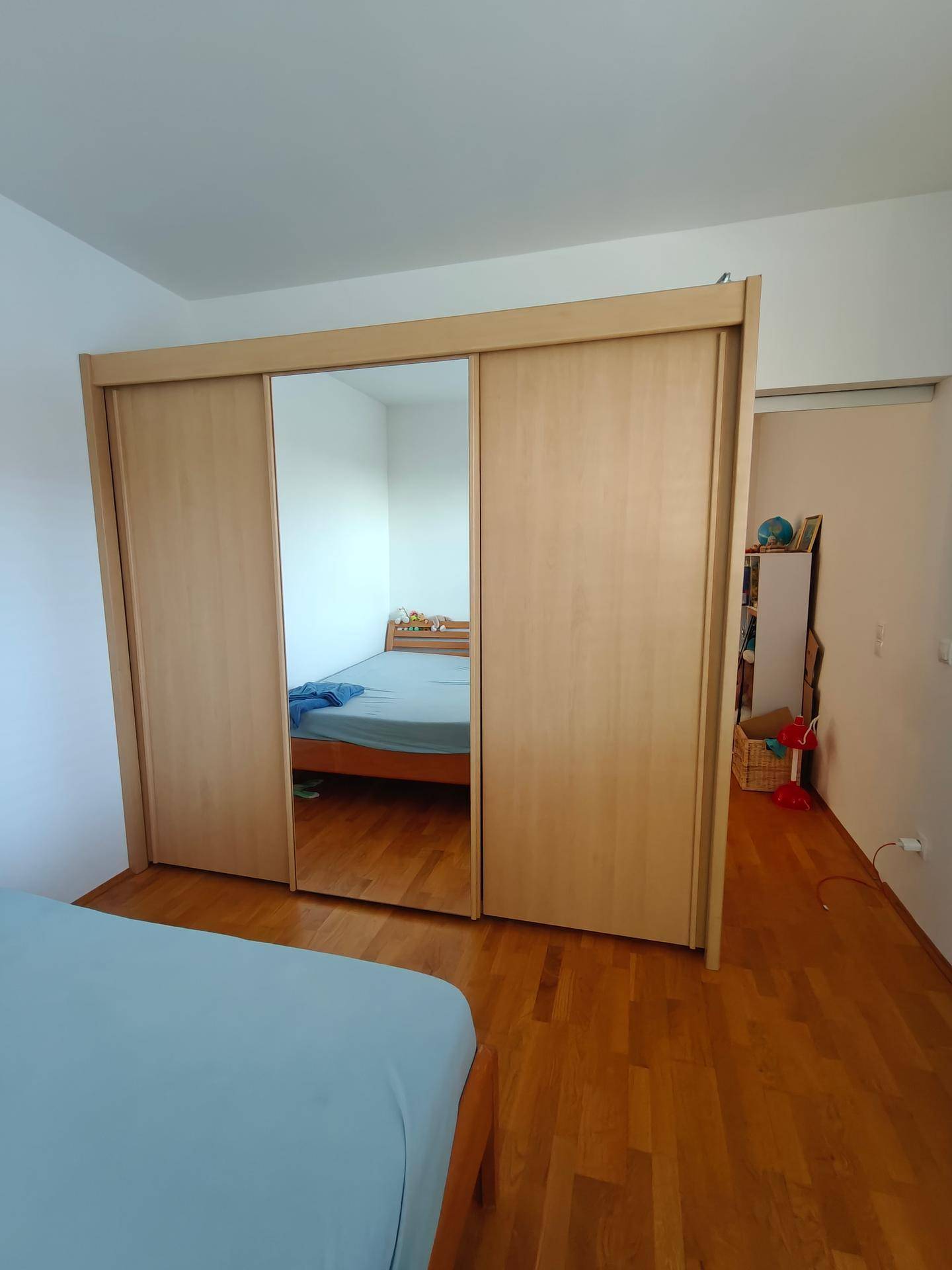 Schlafzimmer mit großem Holzschrank und Spiegeltüren, der viel Stauraum bietet.