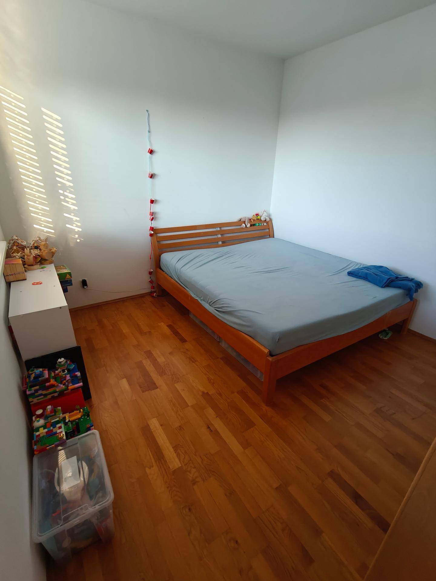 Helles Schlafzimmer mit Holzbett und Holzboden, ideal für ein Kinder- oder Gästezimmer.