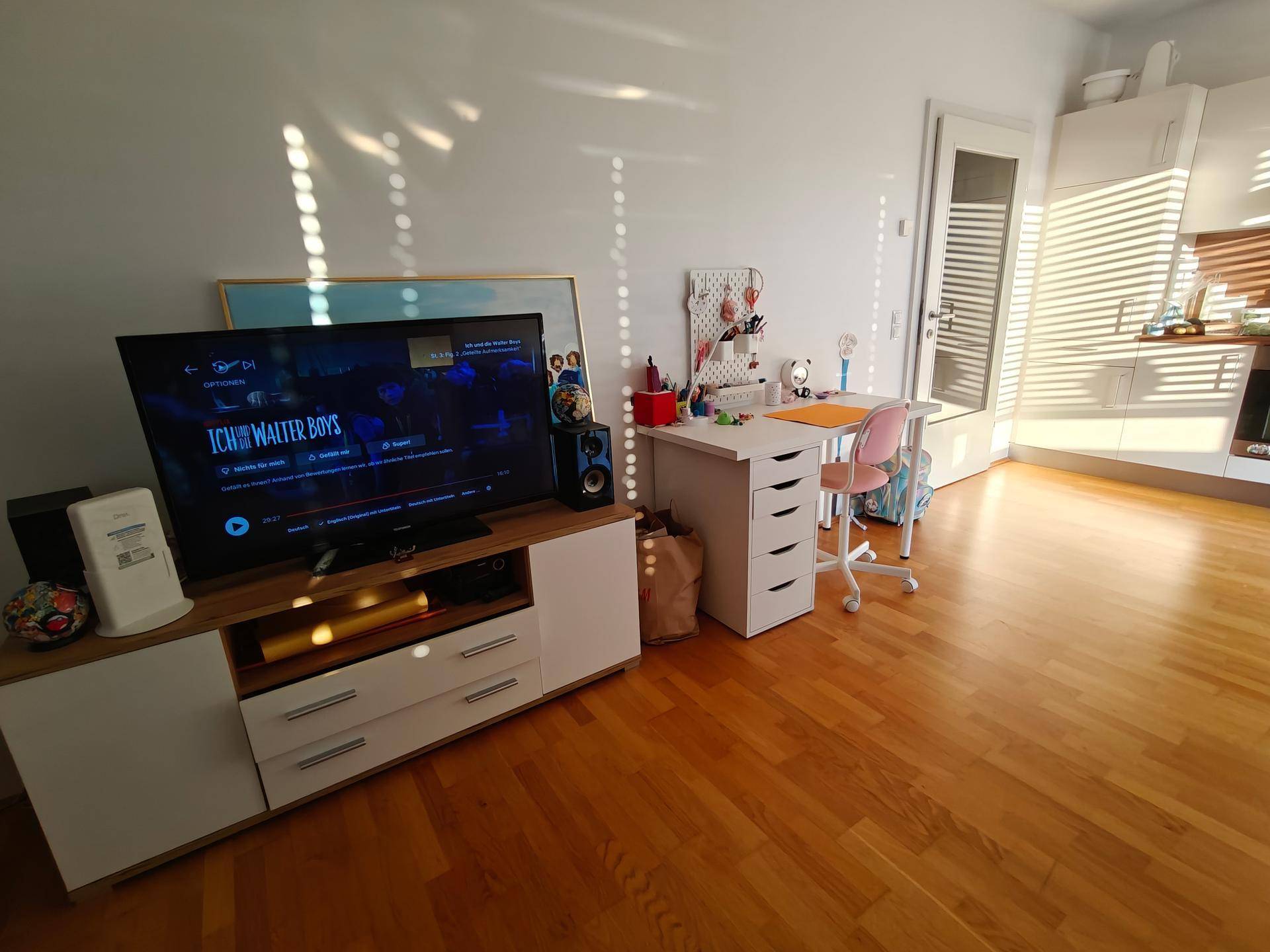 Wohnbereich mit TV-Möbeln und einem kleinen Schreibtisch, der zum Arbeiten einlädt.