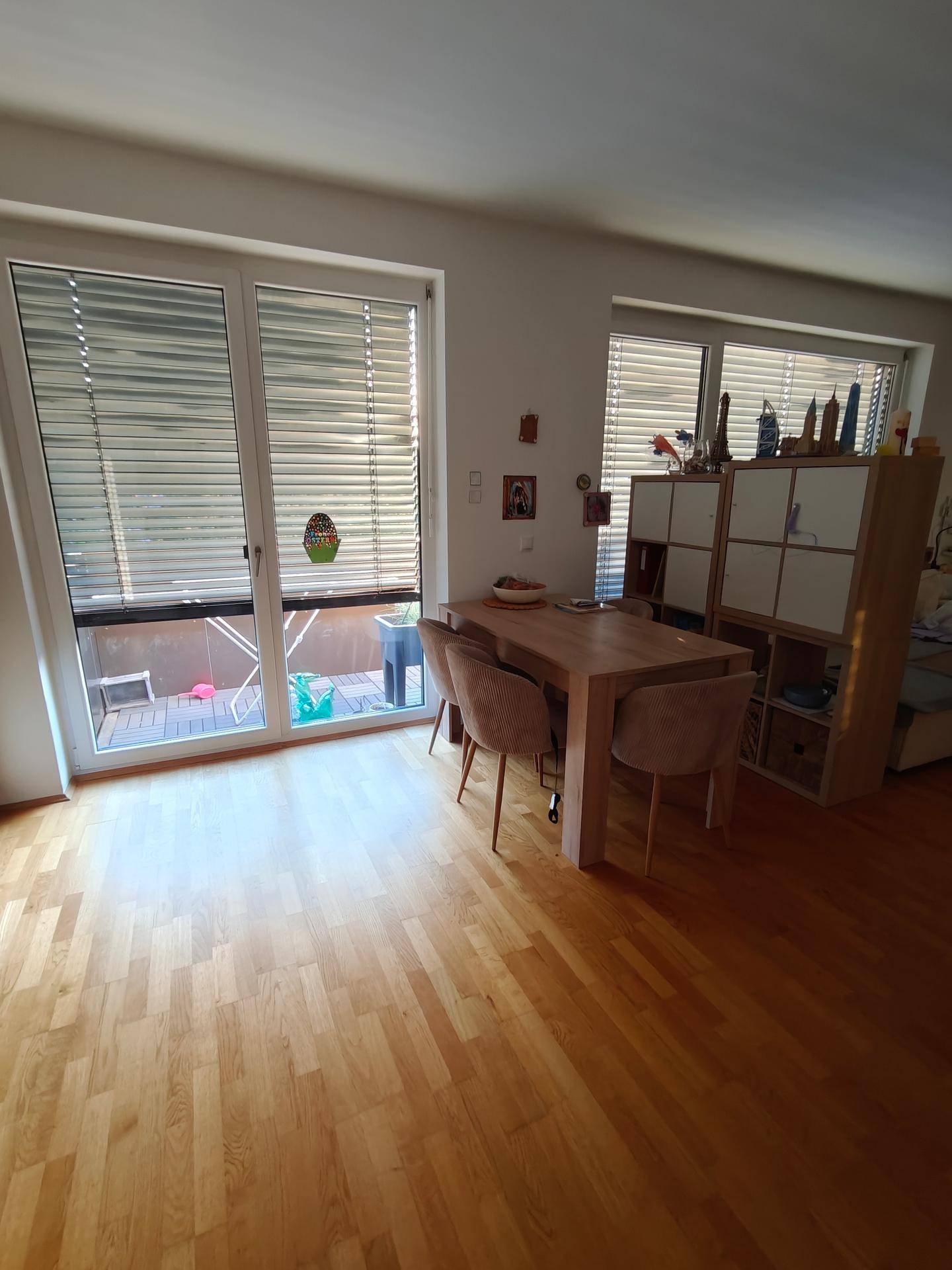 Heller Essbereich mit Holztisch und Stühlen, direkt am Fenster mit Zugang zum Außenbereich.
