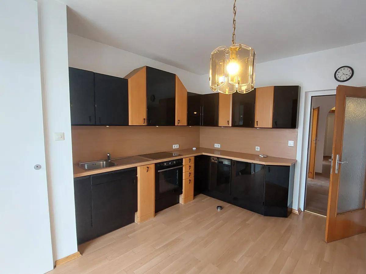 Küche mit schwarzen und holzfarbenen Schränken, integriertem Backofen und Parkettboden.