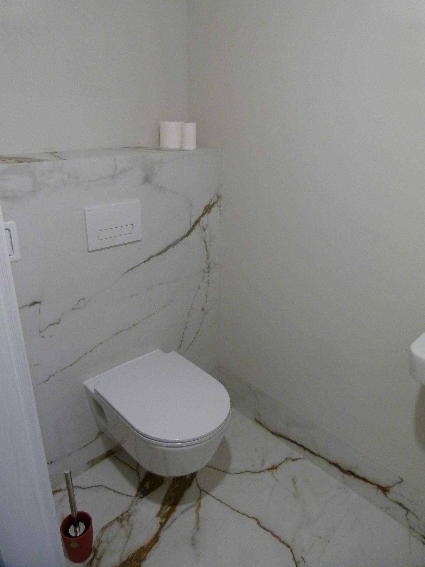 Modernes Gäste-WC mit wandhängender Toilette und eleganten Marmorfliesen.
