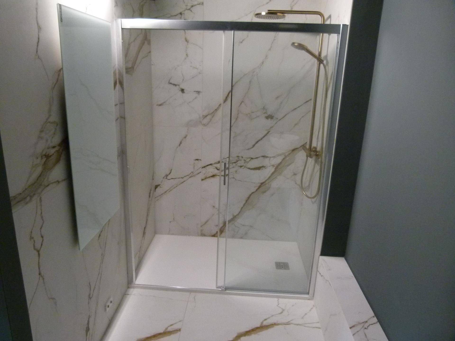 Moderne Duschkabine mit goldenen Armaturen und eleganten Marmorfliesen an Wänden und Boden.
