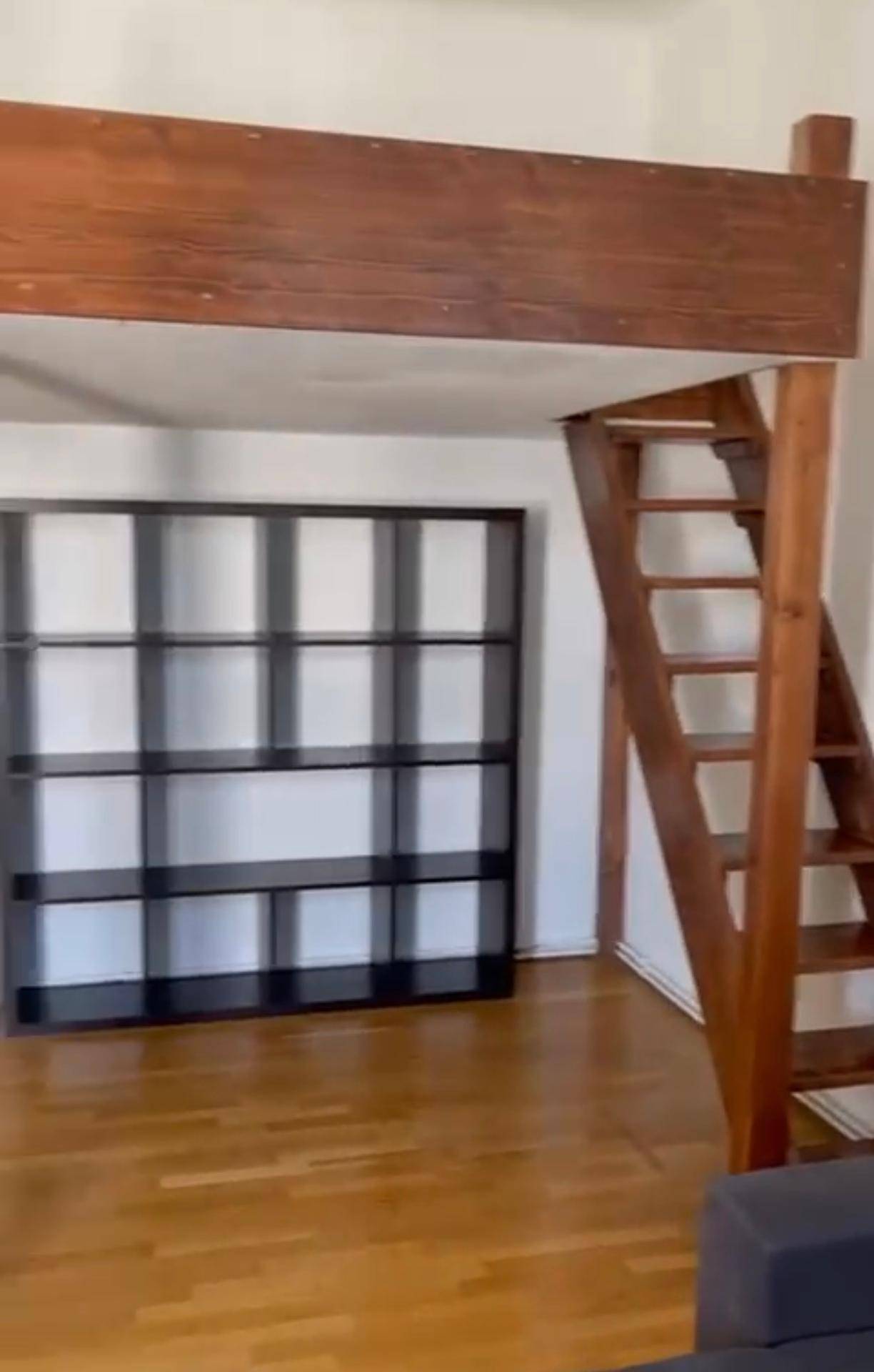 Zimmer mit Holzfußboden, großem Regal und einer Holzkonstruktion für ein Hochbett.
