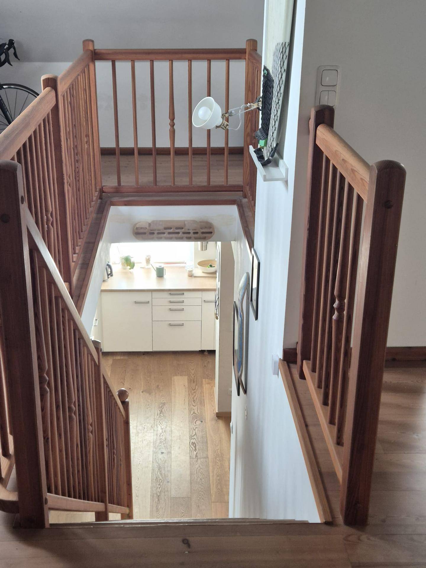 Blick von der Holztreppe hinunter in einen hellen Bereich mit Küchenzeile.