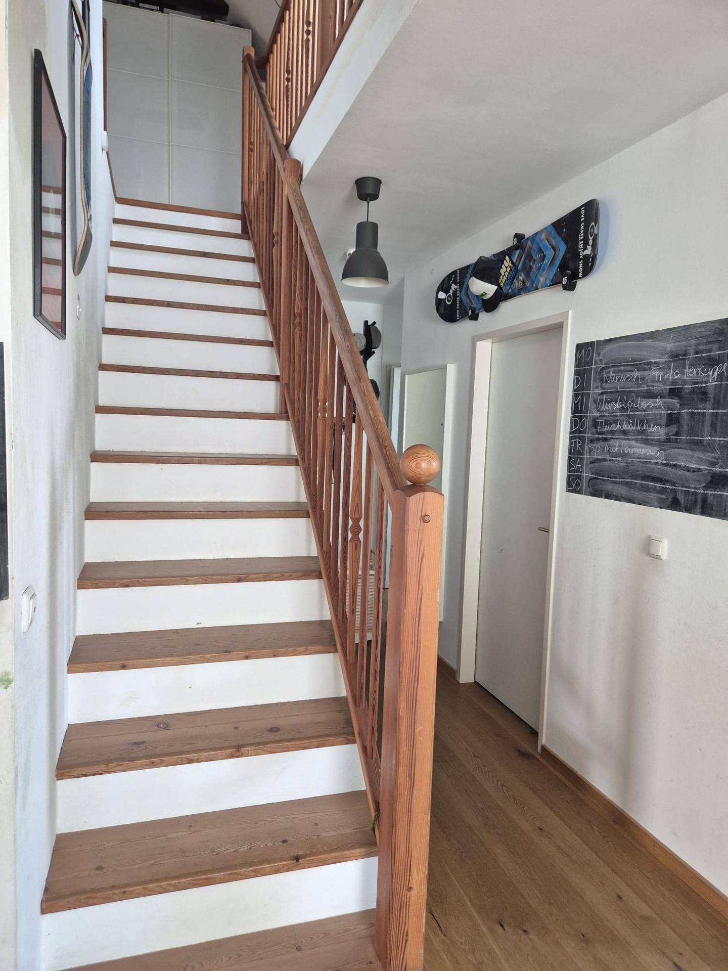 Holztreppe mit Geländer, die zu den oberen Etagen des Hauses führt.