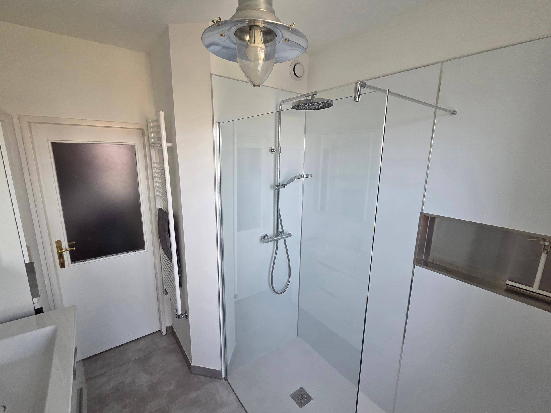 Modernes Badezimmer mit geräumiger begehbarer Dusche und praktischem Handtuchheizkörper.