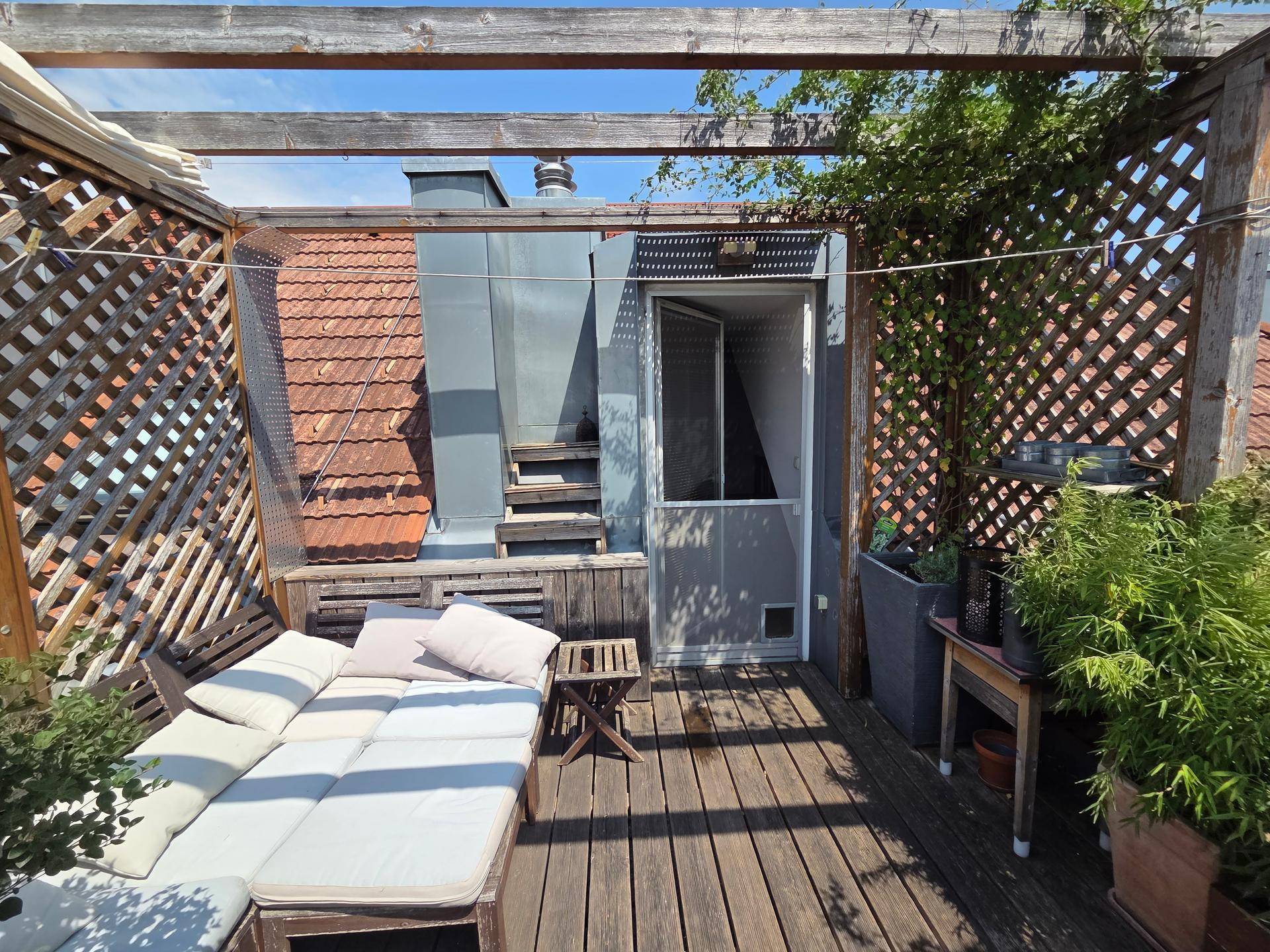 Gemütliche Dachterrasse mit Holzdeck, Pergola und einer bequemen Lounge-Sitzgruppe.