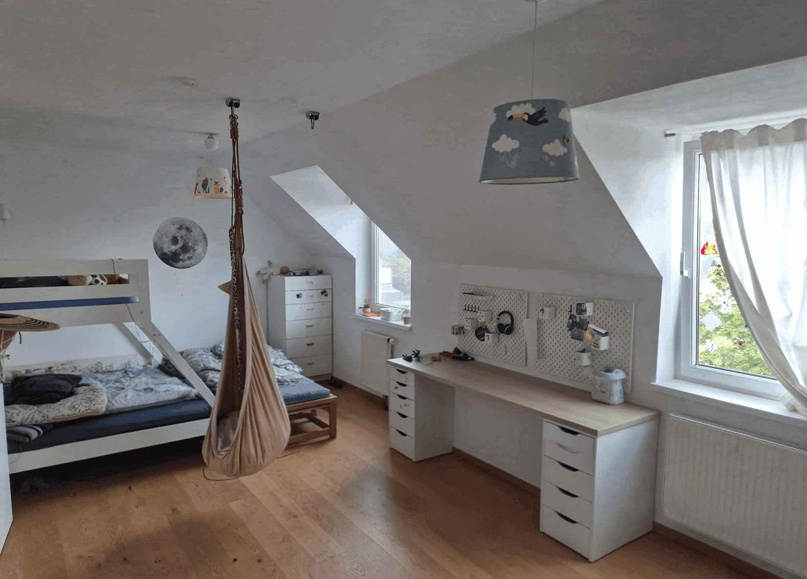 Helles Kinderzimmer mit Holzboden, Schreibtisch, Etagenbett und Dachschrägen.