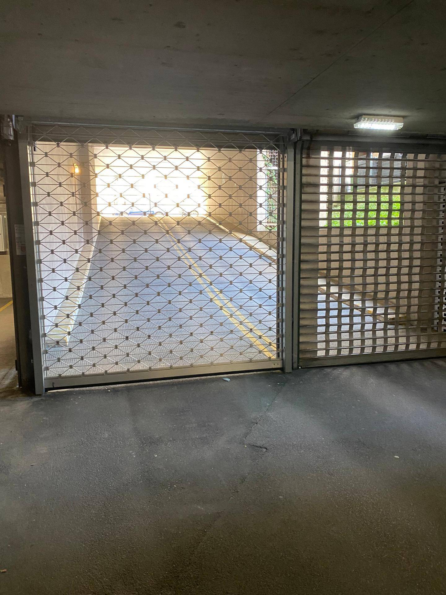 Metallrolltor am Eingang einer Tiefgarage, das Licht von außen hereinlässt.