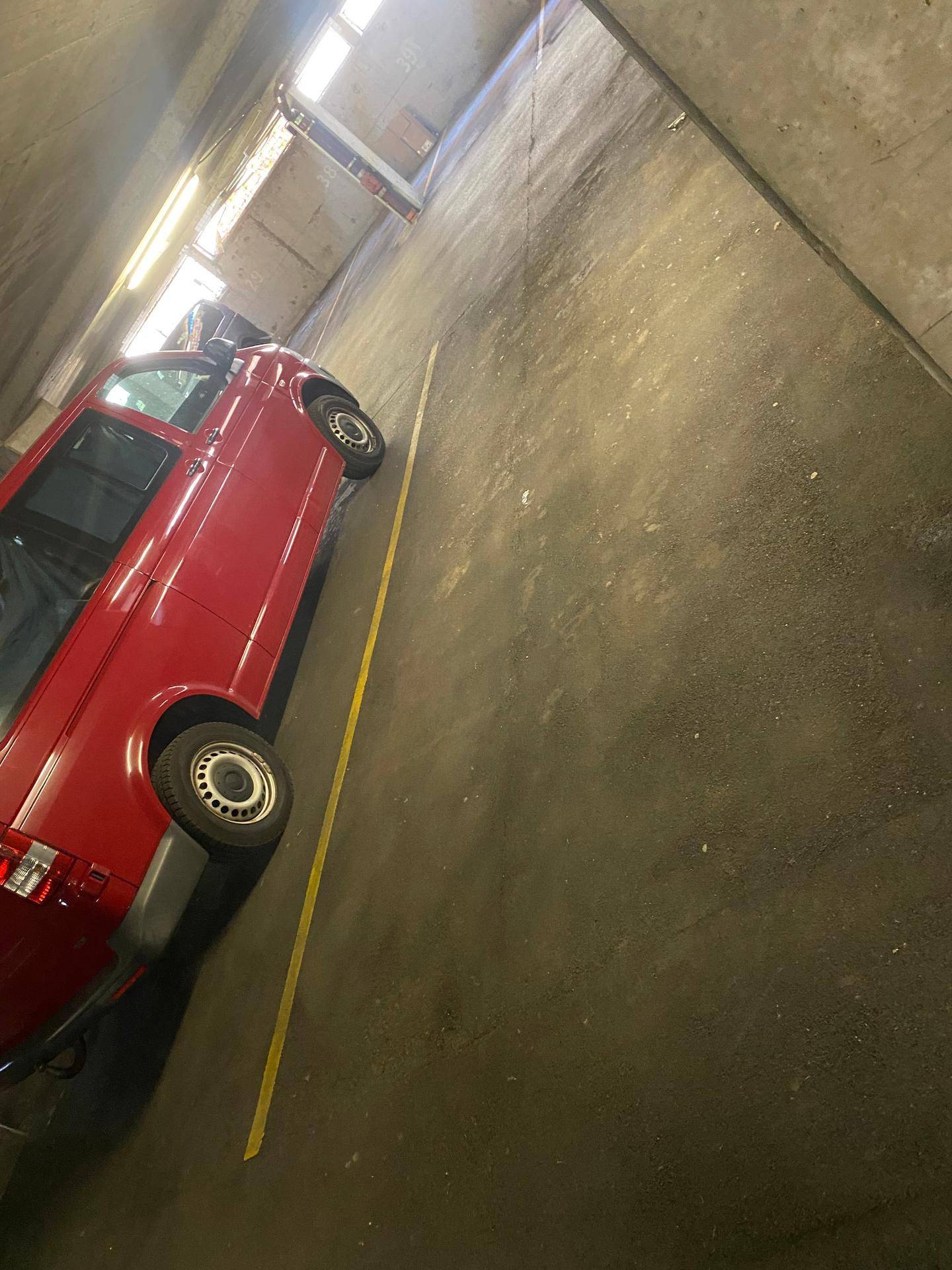 Roter Van auf einem Stellplatz in der Tiefgarage mit gelben Markierungen.