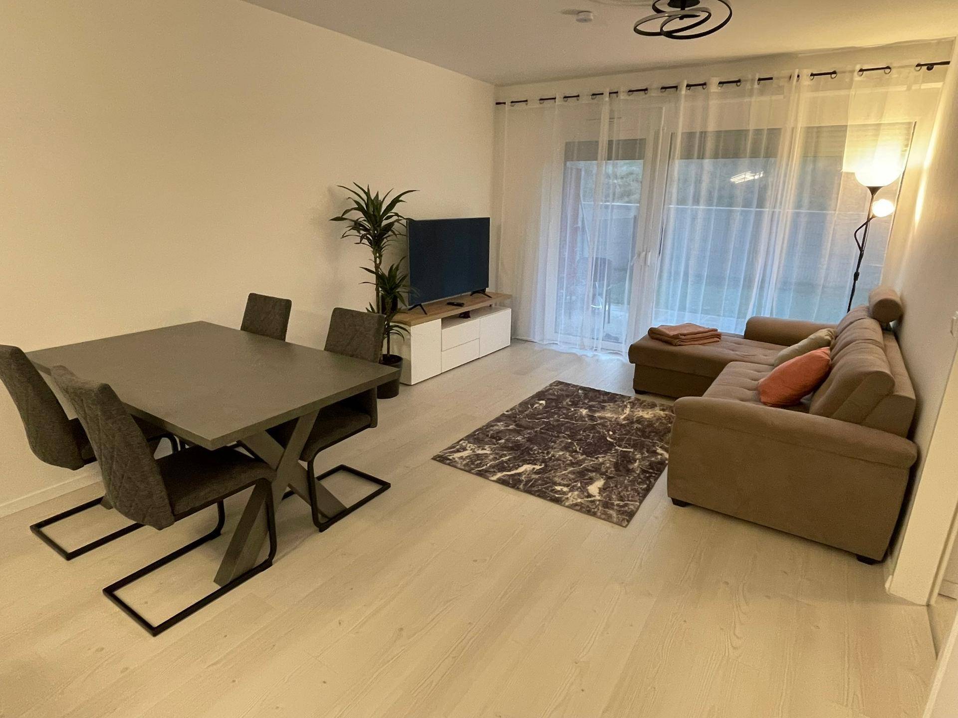 Gemütlicher Wohn- und Essbereich mit Sofa, Esstisch und Zugang zur Terrasse.