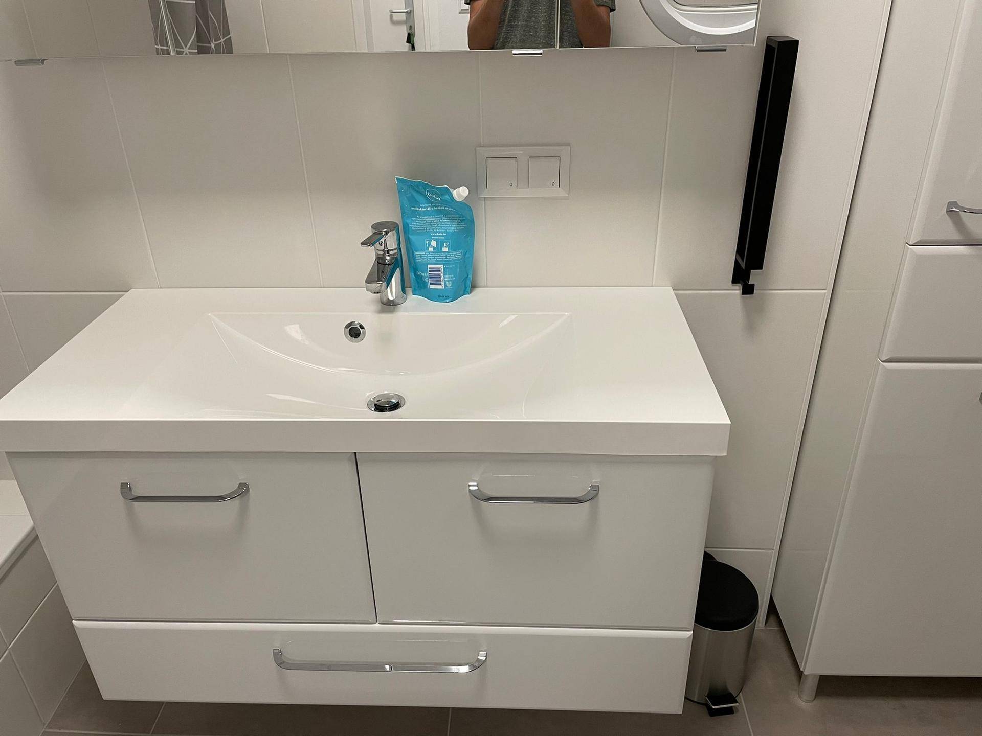 Modernes Badezimmer mit weißem Waschtischunterschrank und großem Spiegel.