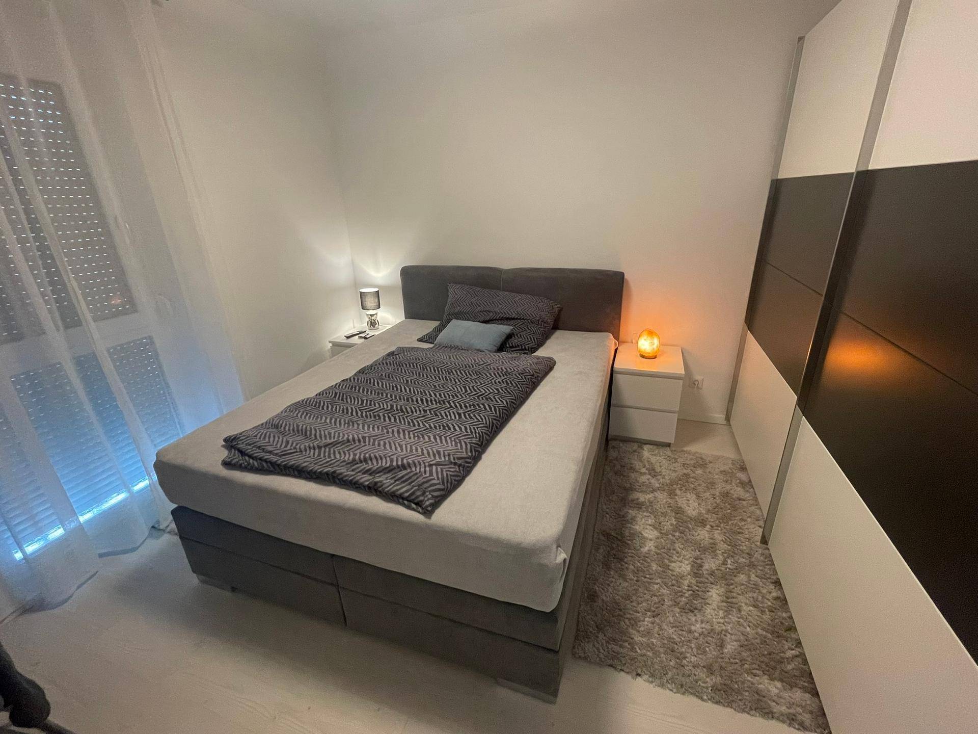 Modernes Schlafzimmer mit Doppelbett, Nachttischen und integriertem Kleiderschrank.