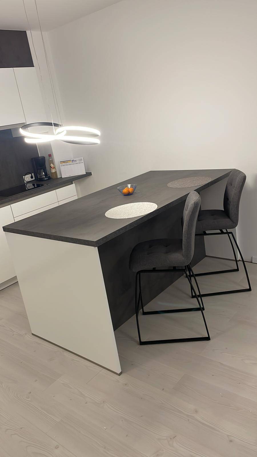 Stilvolle Kücheninsel mit integrierter Bar und modernen Barhockern, ideal für schnelle Mahlzeiten.