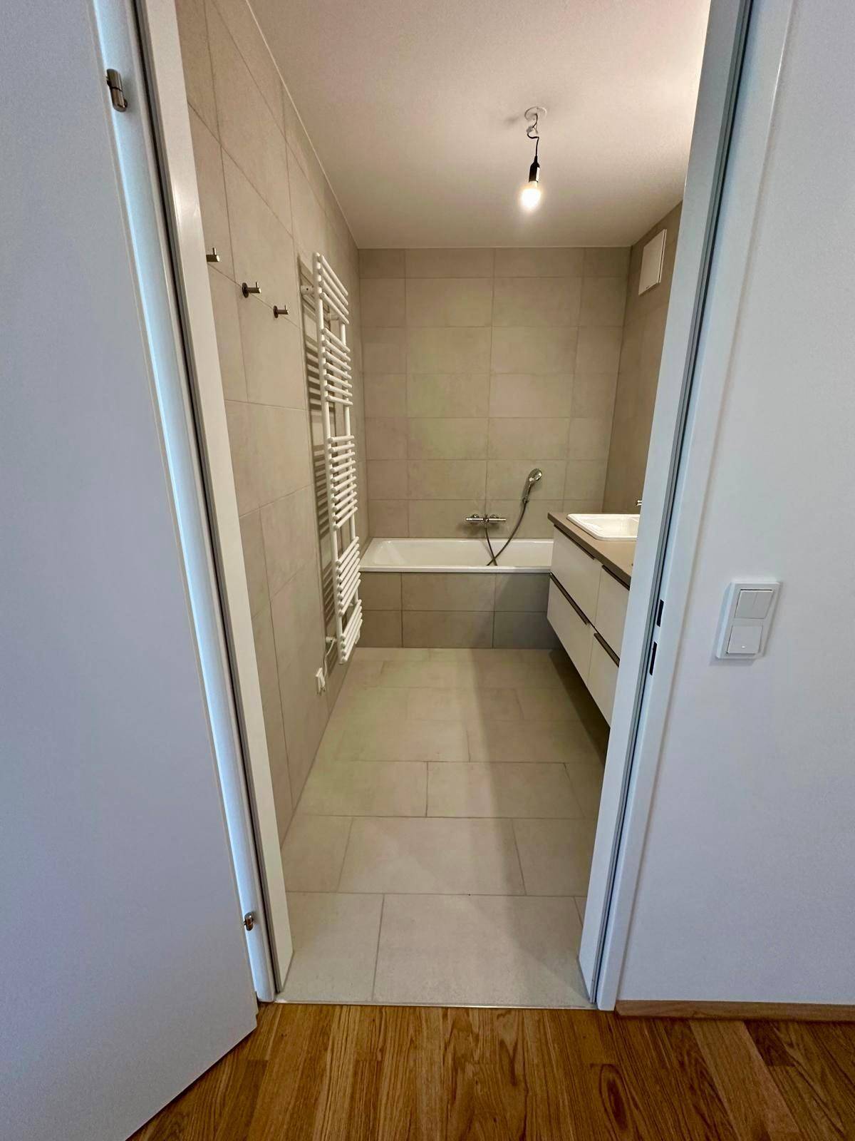 Modernes Badezimmer mit Badewanne, Doppelwaschbecken und hellen Fliesen.