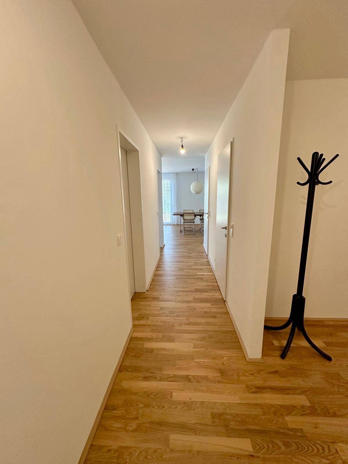 Langer Flur mit Holzboden und Garderobe, der zu den Wohnbereichen führt.