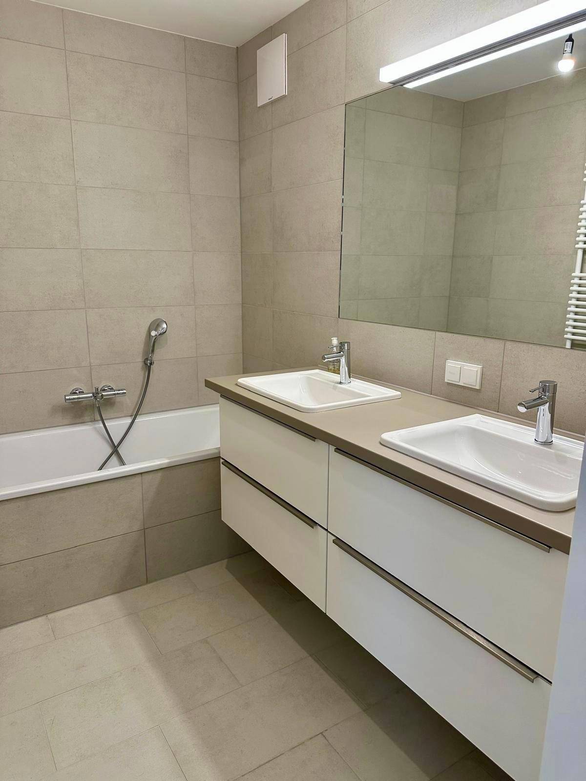 Doppelwaschbecken mit großem Spiegel und Badewanne im modernen Badezimmer.