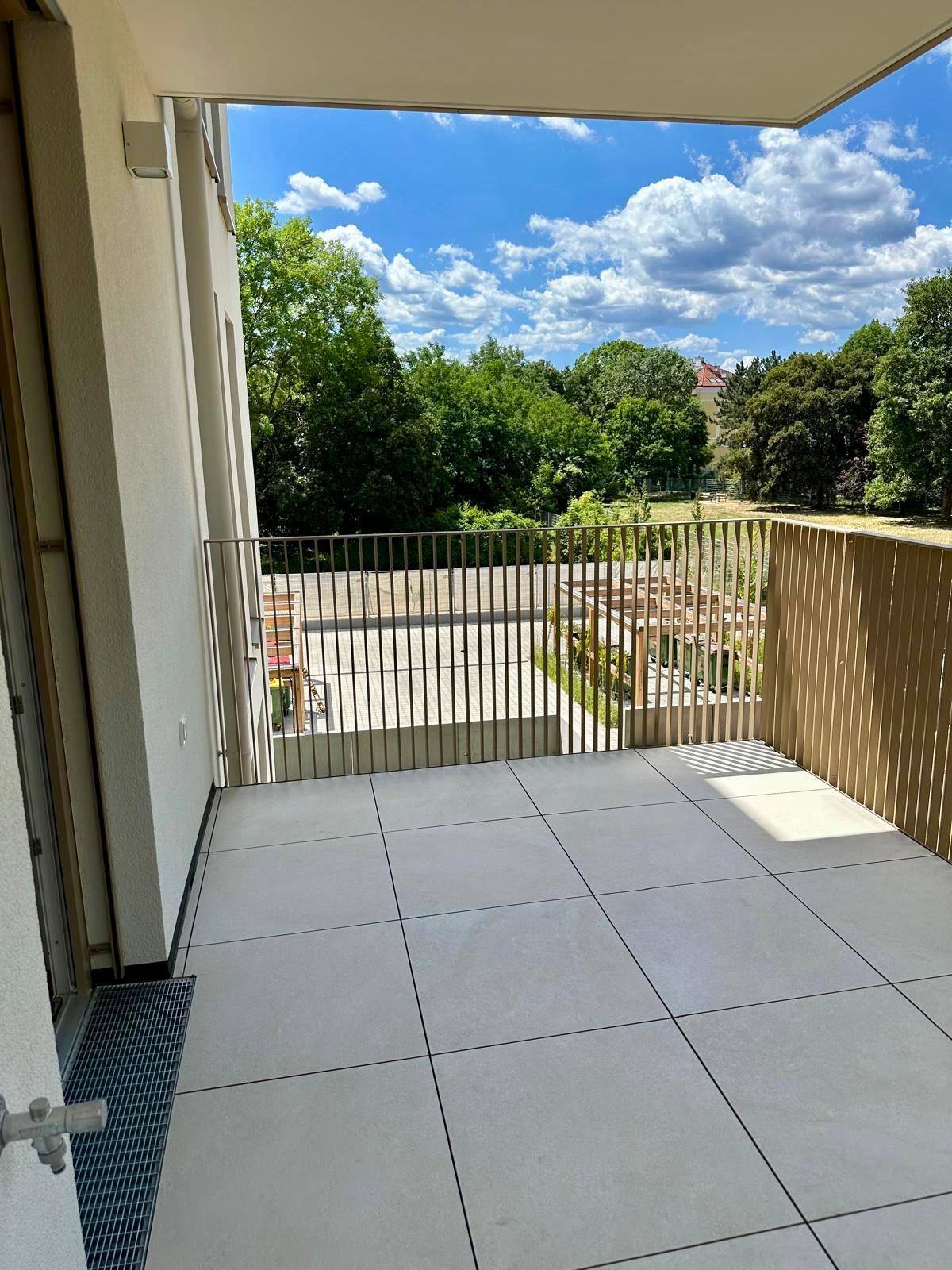 Heller Balkon mit Fliesenboden und weitem Blick in die Umgebung.