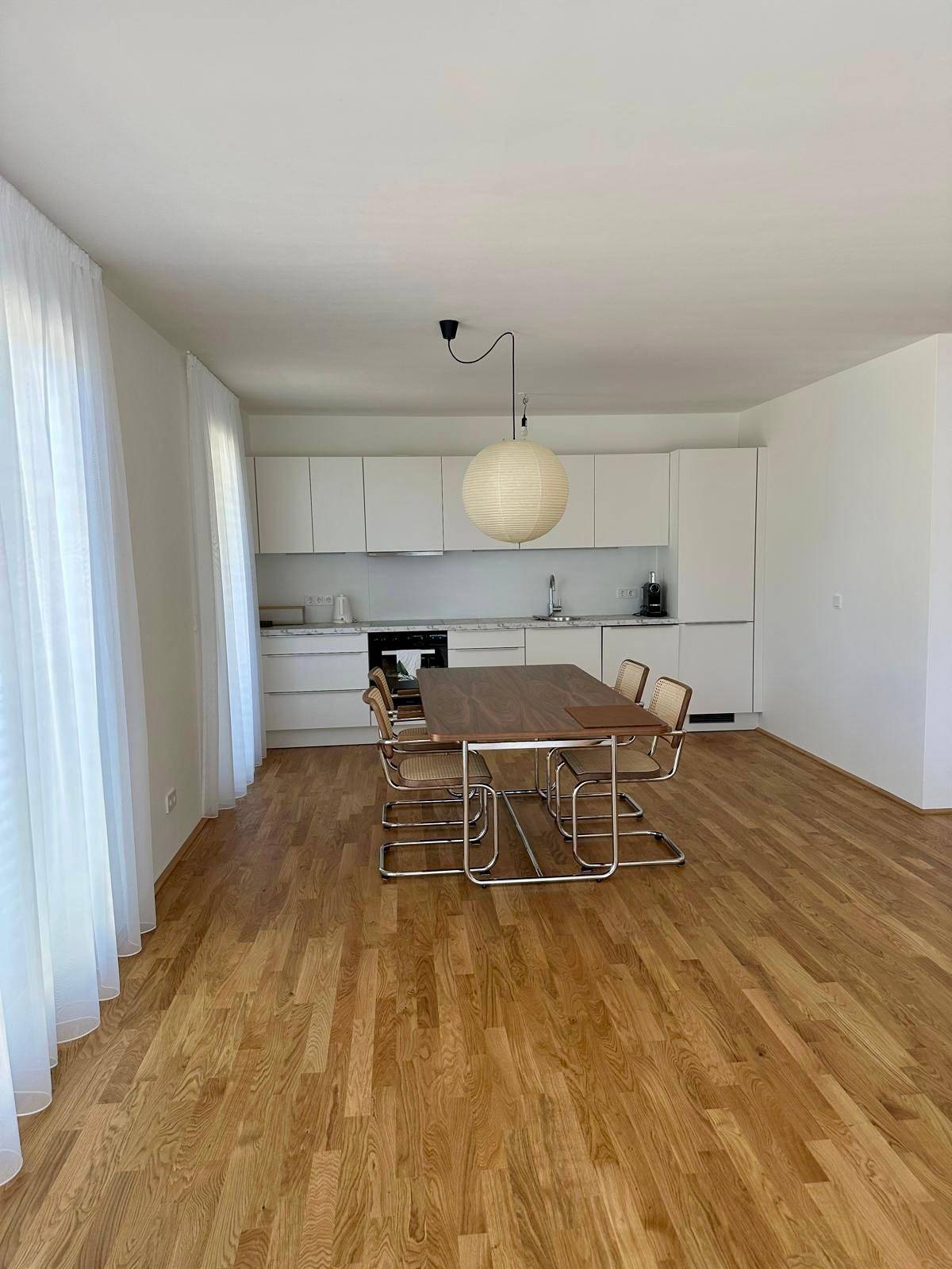 Offener Wohn-Essbereich mit moderner Küche, Holzboden und viel Tageslicht.