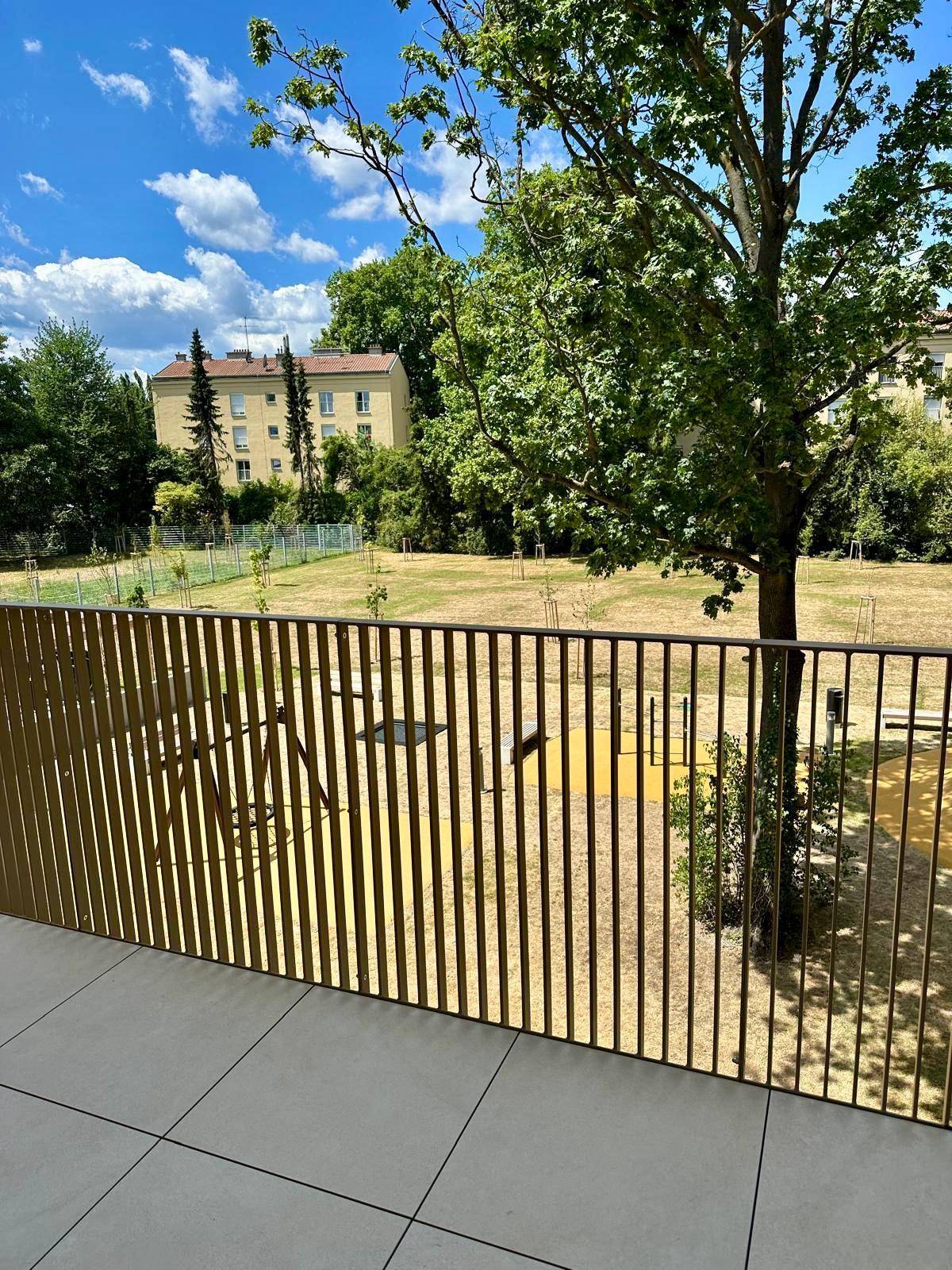 Balkon mit Blick auf eine Grünfläche und angrenzende Gebäude.