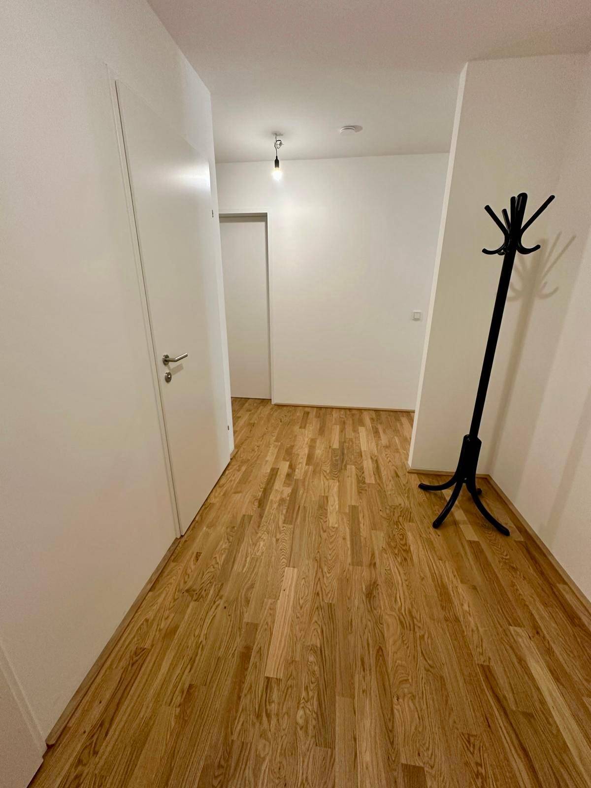 Geräumiger Flur mit Holzparkettboden und einem praktischen Garderobenständer für Jacken und Mäntel.