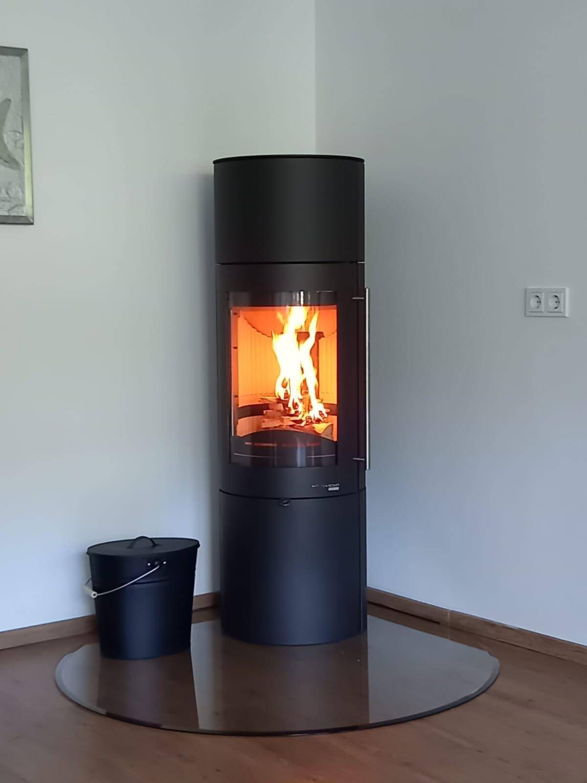 Moderner schwarzer Holzofen mit sichtbarem Feuer, der eine gemütliche Atmosphäre schafft.