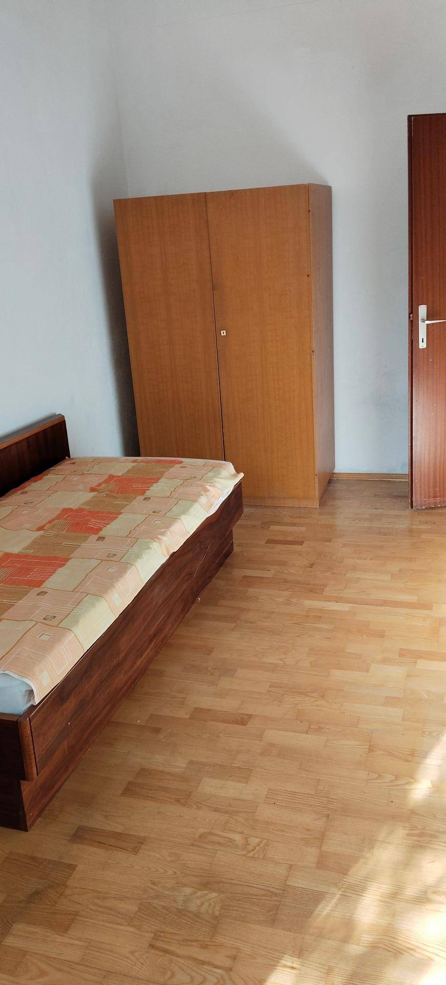 Schlafzimmer mit Holzbett, großem Kleiderschrank und Holztür, bietet ausreichend Stauraum.