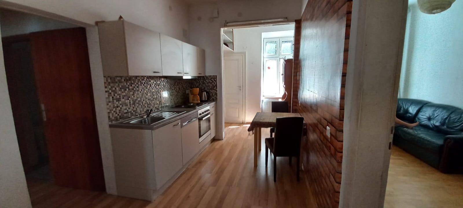 Funktionale Küche mit hellen Schränken, Mosaikfliesen und Essbereich, ausgestattet mit Holzboden.