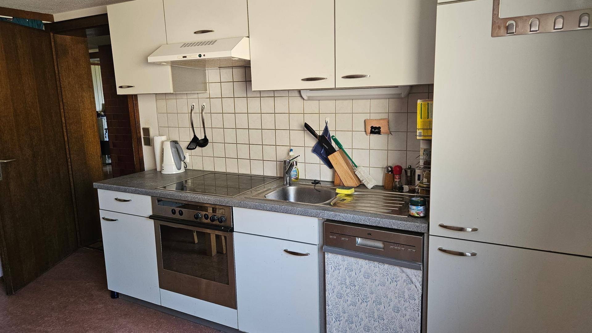 Funktionale Küche mit weißen Schränken, Einbaugeräten und Fliesenrückwand.