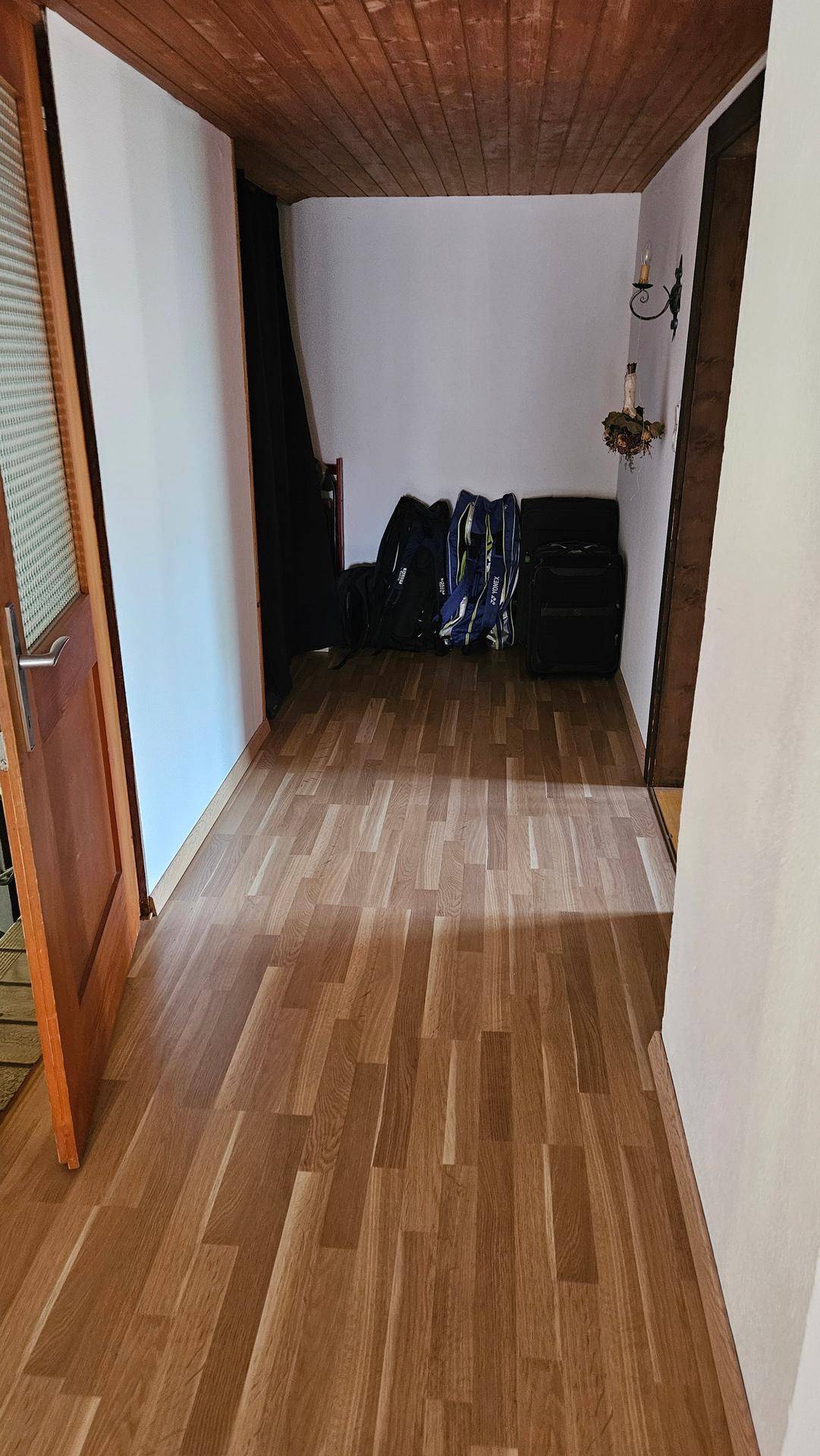 Heller Flur mit Laminatboden und weißen Wänden, der zu weiteren Räumen führt.
