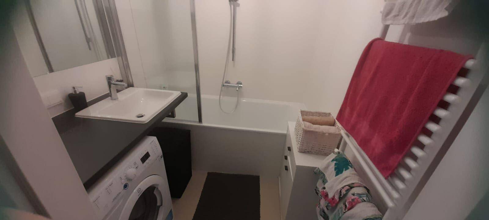 Funktionales Badezimmer mit Badewanne, Duschfunktion, Waschbecken und beheiztem Handtuchhalter.