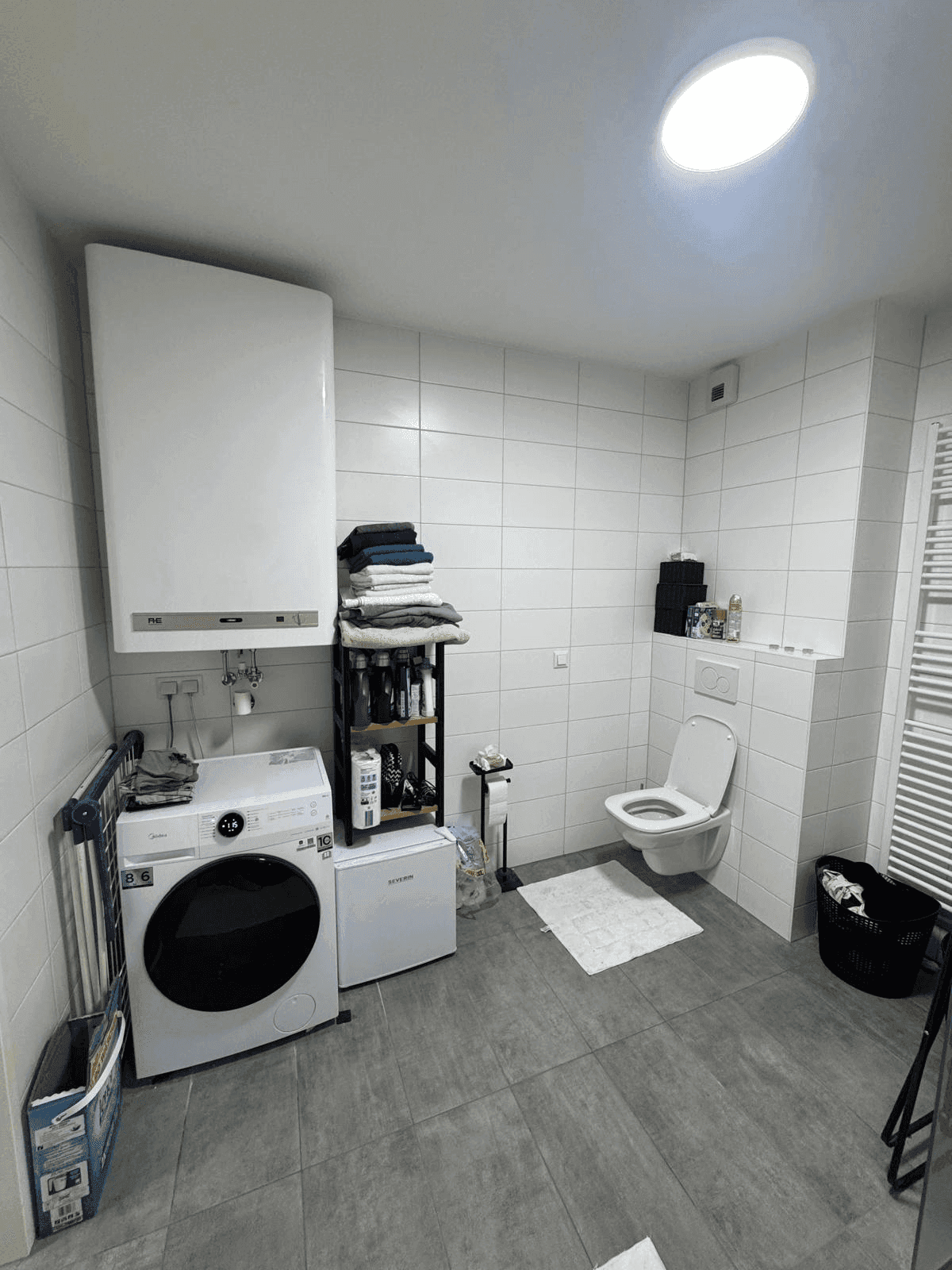Badezimmer mit Waschmaschine, Trockner und wandhängendem WC.