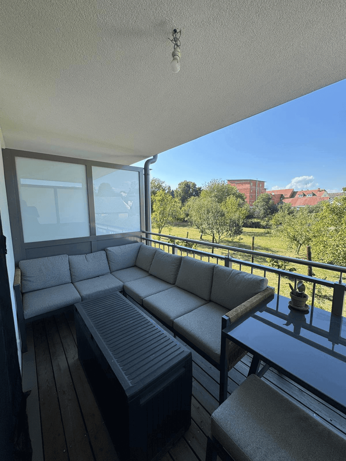 Großer Balkon mit L-förmiger Sitzgruppe und weitem Blick ins Grüne.