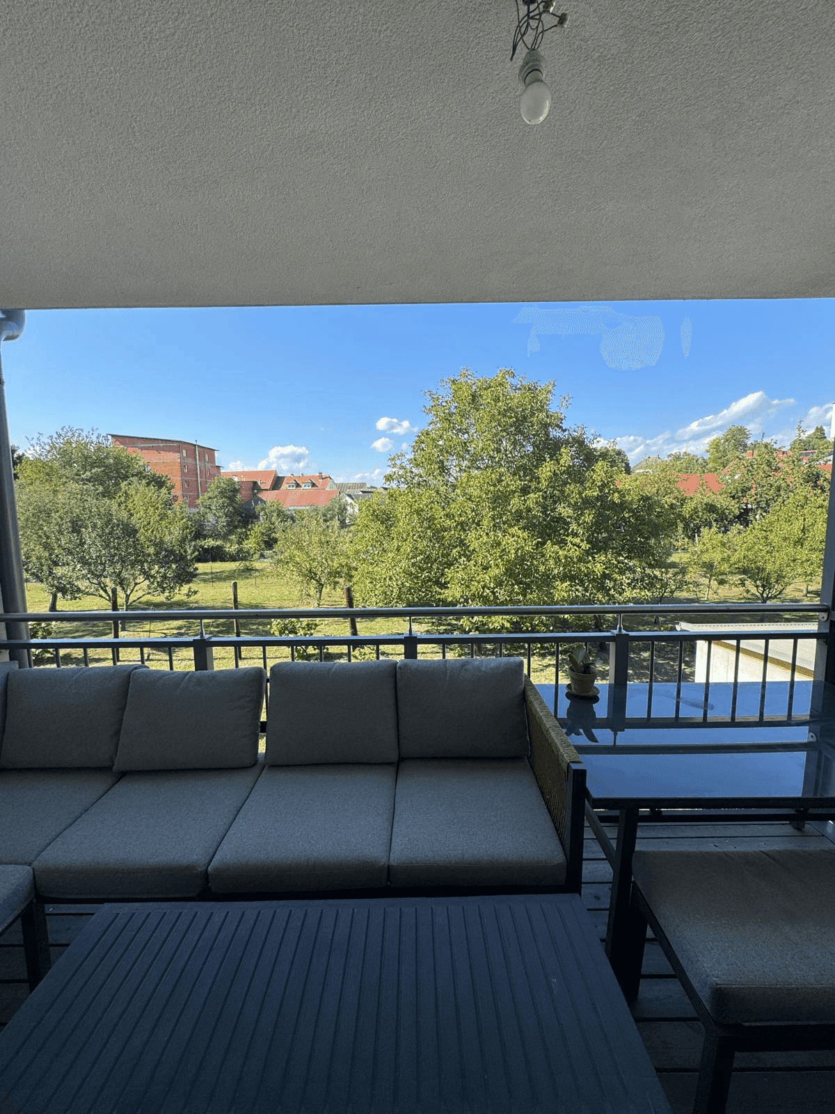 Balkon mit bequemer Sitzgelegenheit und freiem Blick auf Bäume und Landschaft.