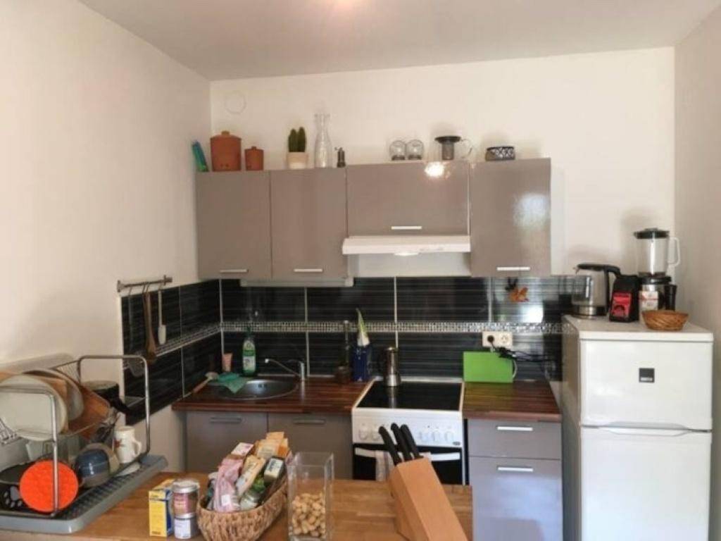 Funktionale Küche mit grauen Oberschränken, dunklem Fliesenspiegel und einer Holz-Arbeitsplatte.