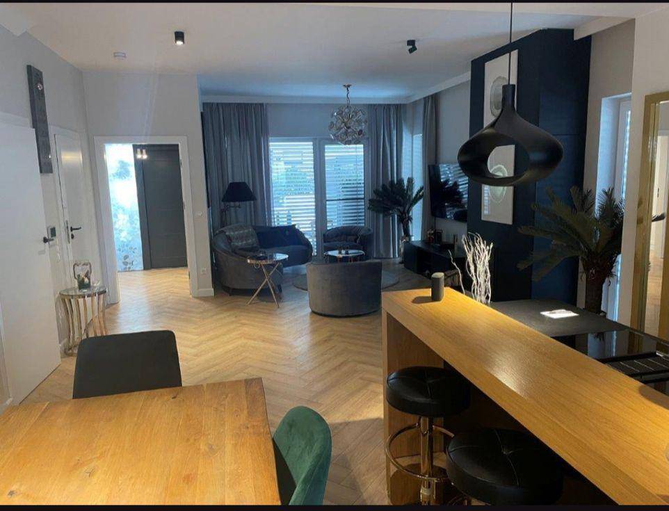 Offener Wohn- und Essbereich mit Kücheninsel, Fischgrätparkett und Zugang zum Wohnzimmer.