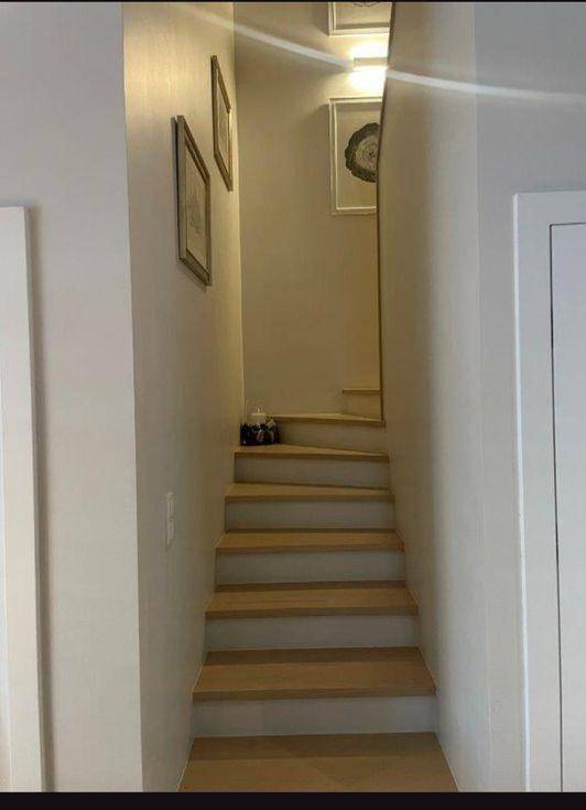 Schmale Holztreppe mit minimalistischer Dekoration, die zu den oberen Etagen führt.