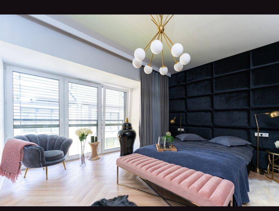 Elegantes Schlafzimmer mit großem Bett, gepolstertem Kopfteil und bodentiefen Fenstern.