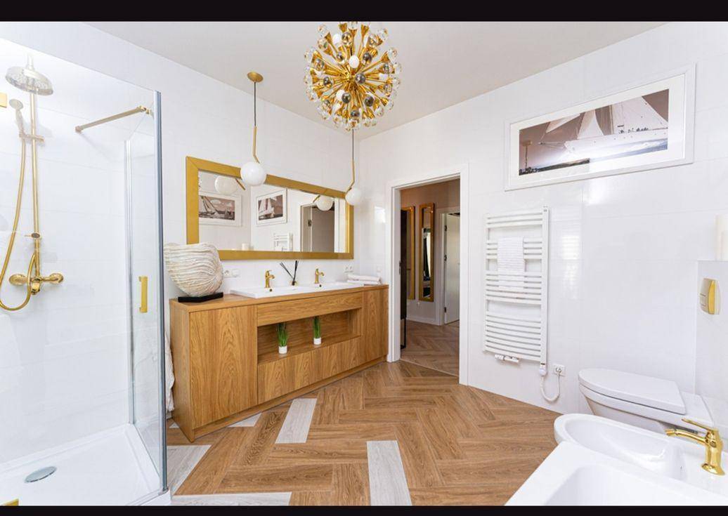 Luxuriöses Badezimmer mit Doppelwaschbecken, Dusche, Bidet und stilvollen Goldakzenten.