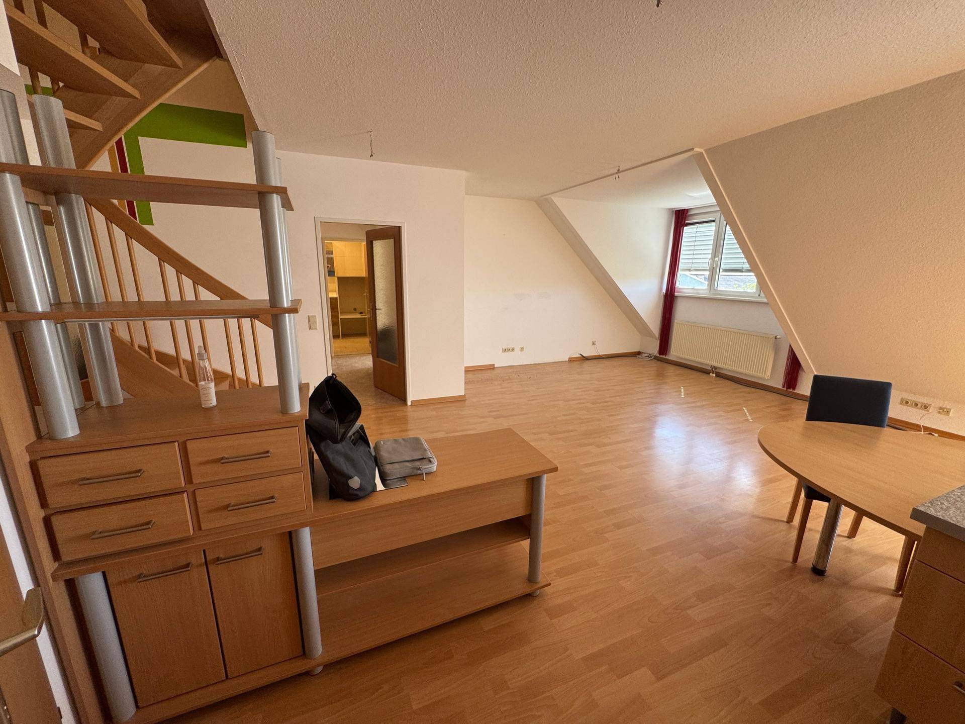 Geräumiger Wohn- und Essbereich mit Laminatboden, Dachschrägen und einer Wendeltreppe.